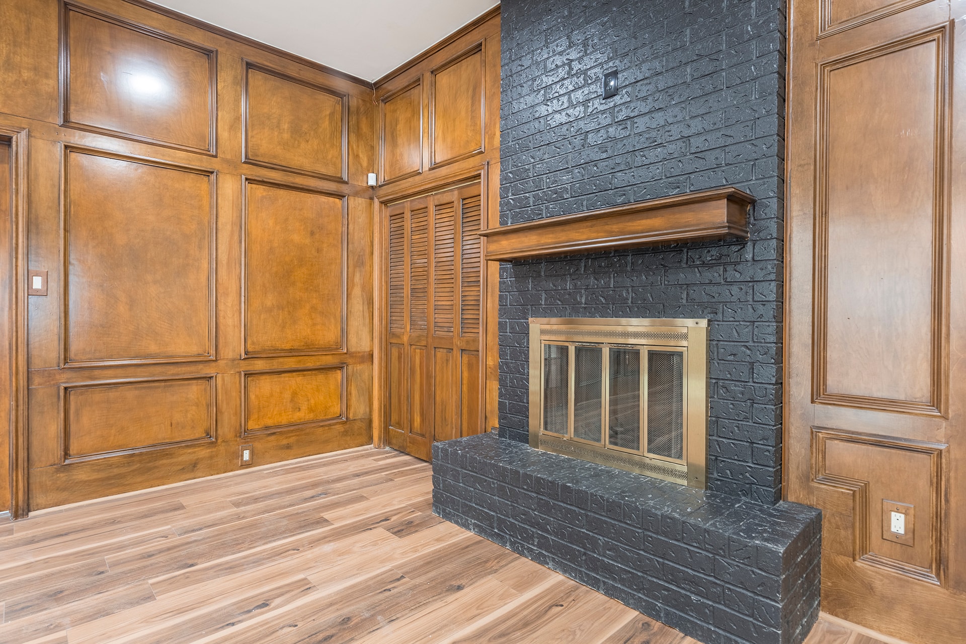 Wood paneled room with black brick fireplace