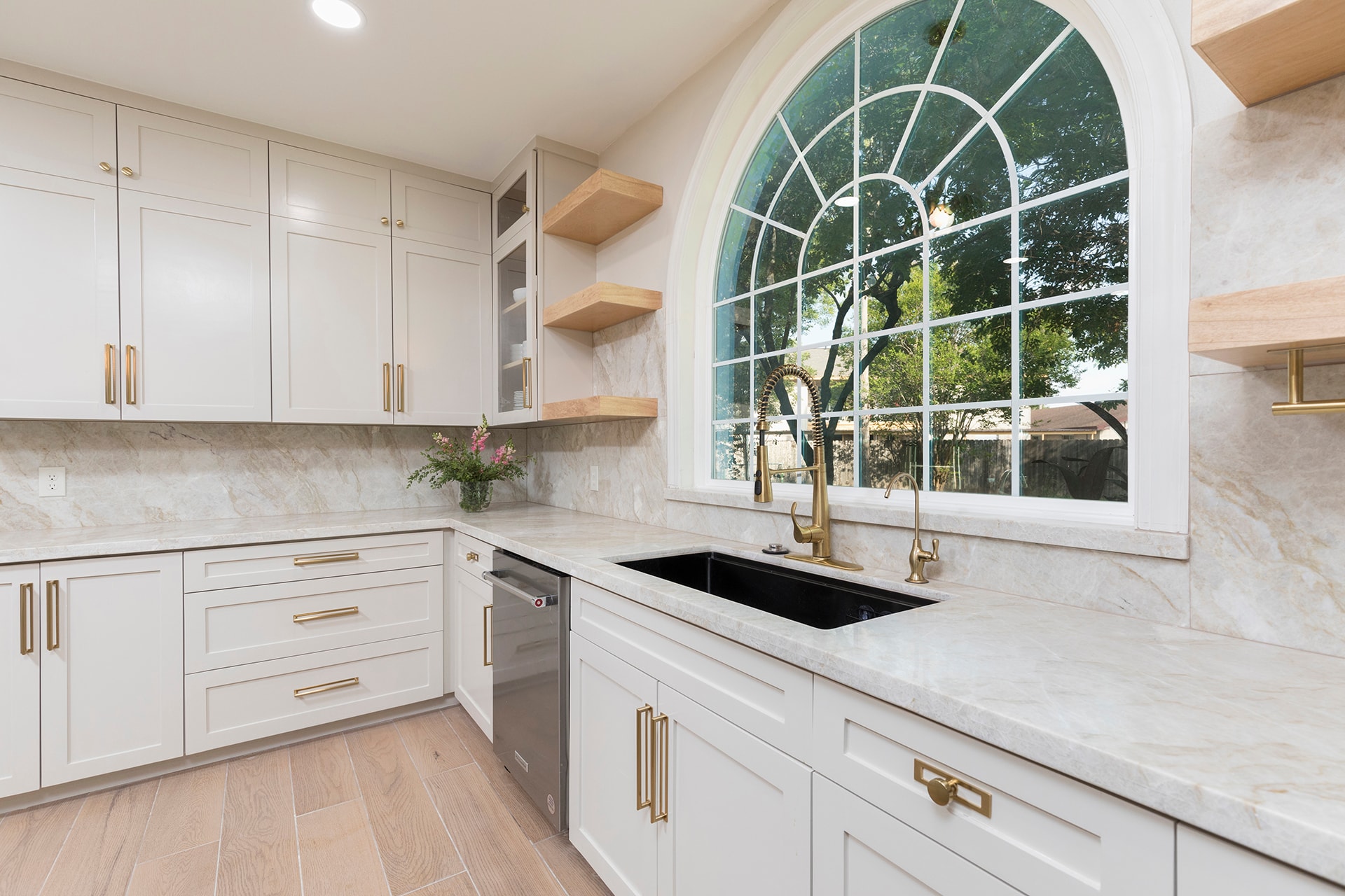 Modern white kitchen with arched window and marble backsplash