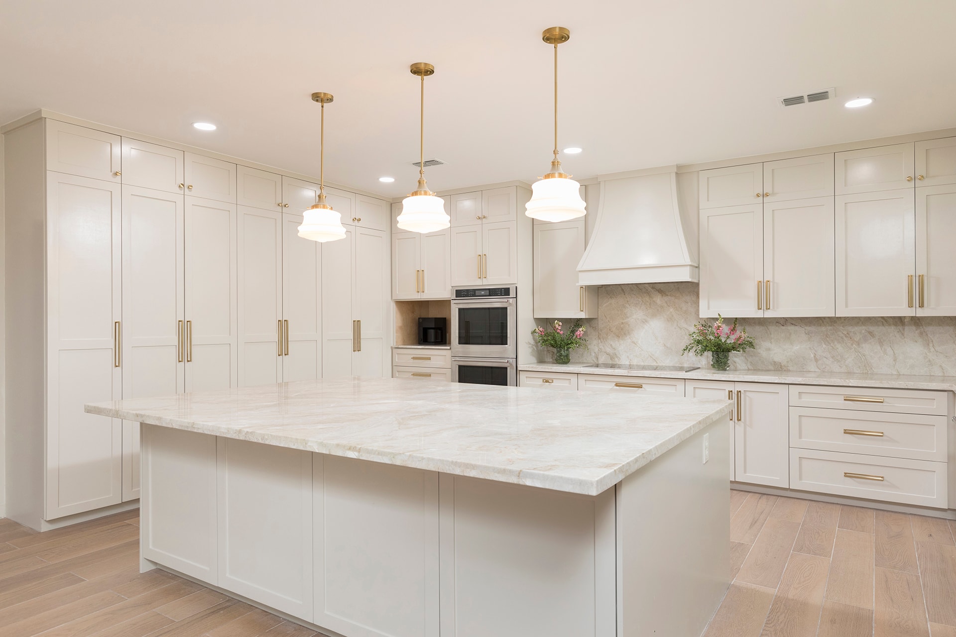 Modern white kitchen with marble island and gold pendants