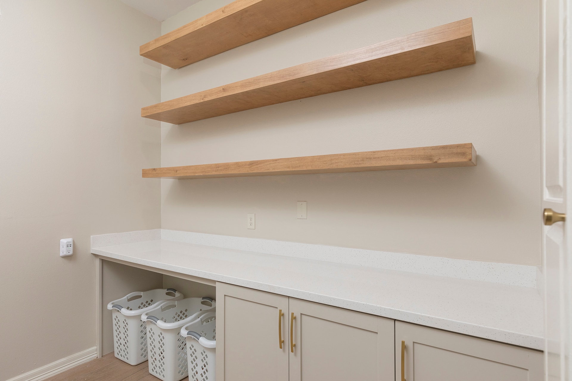 Laundry room with wooden floating shelves and white cabinetry