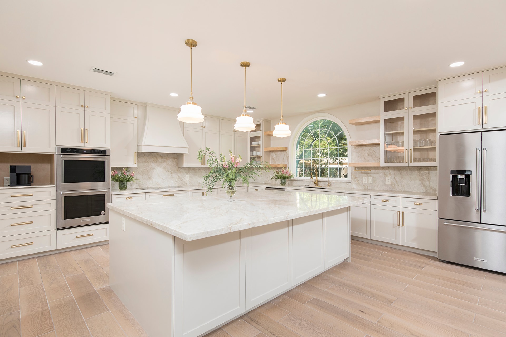 Luxury kitchen with marble island gold pendants and arched window