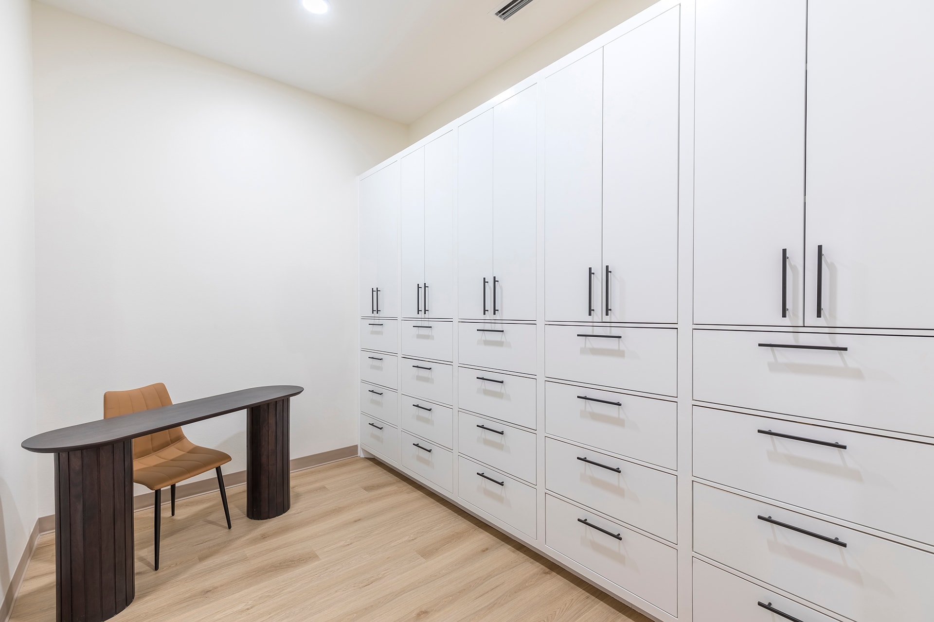Modern closet with white cabinetry and desk